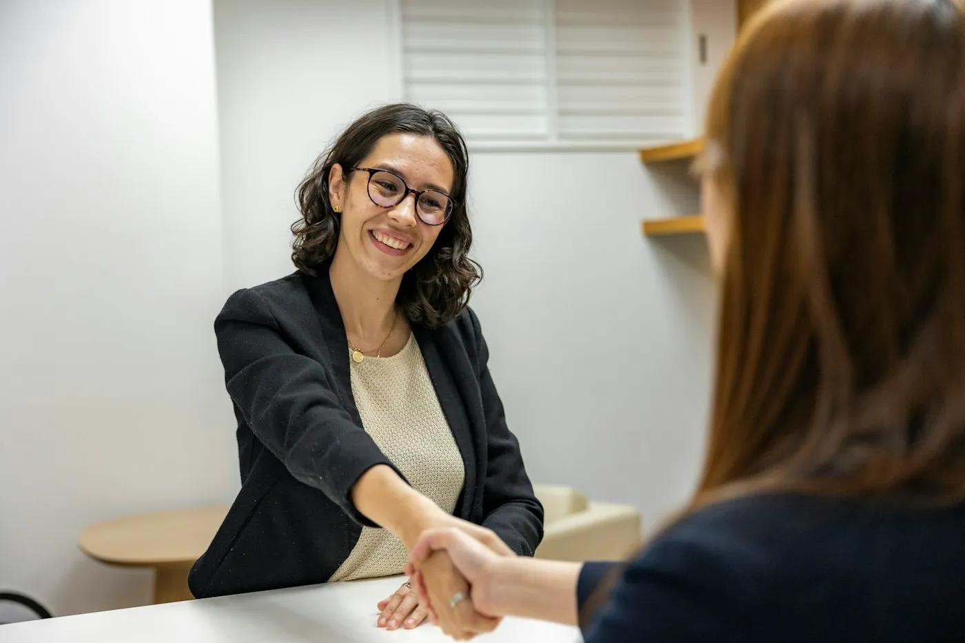 Two professionals shaking hands across a table